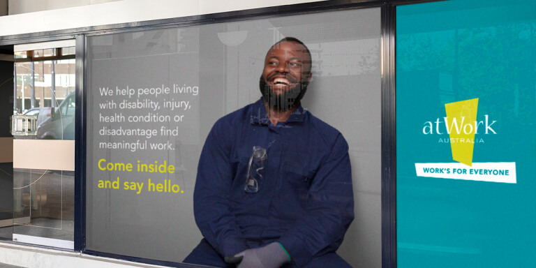 atWork Australia bus station ad featuring smiling man and block quote, designed by MOO Marketing & Design graphic design agency in Melbourne